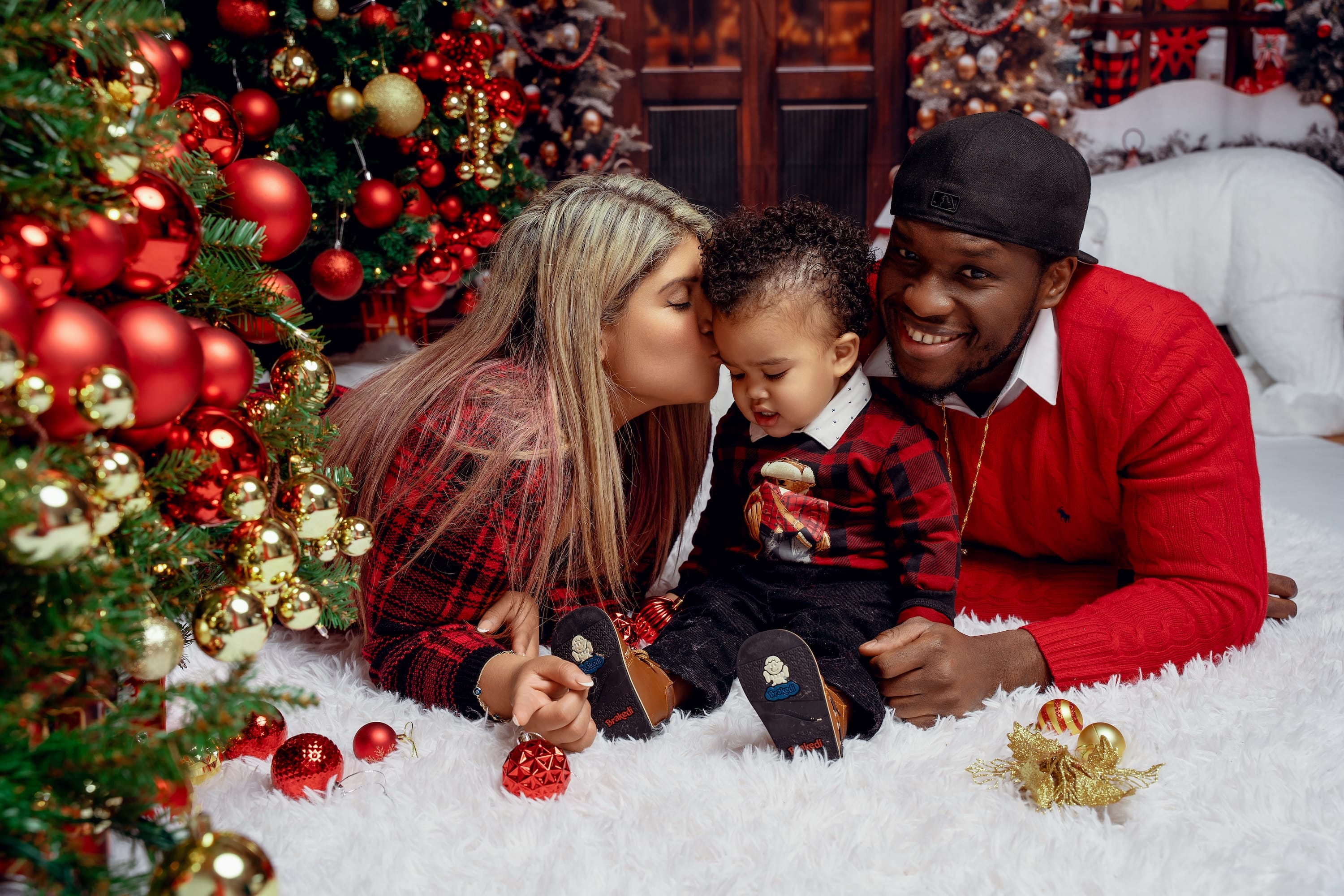 Family laughing together on the floor beside a decorated Christmas tree