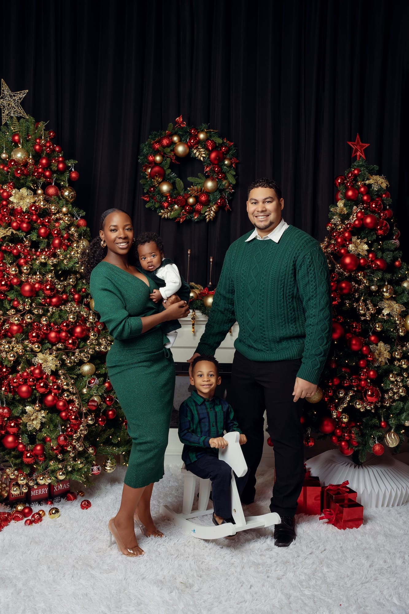 Family in green outfits posing beside a decorated Christmas tree