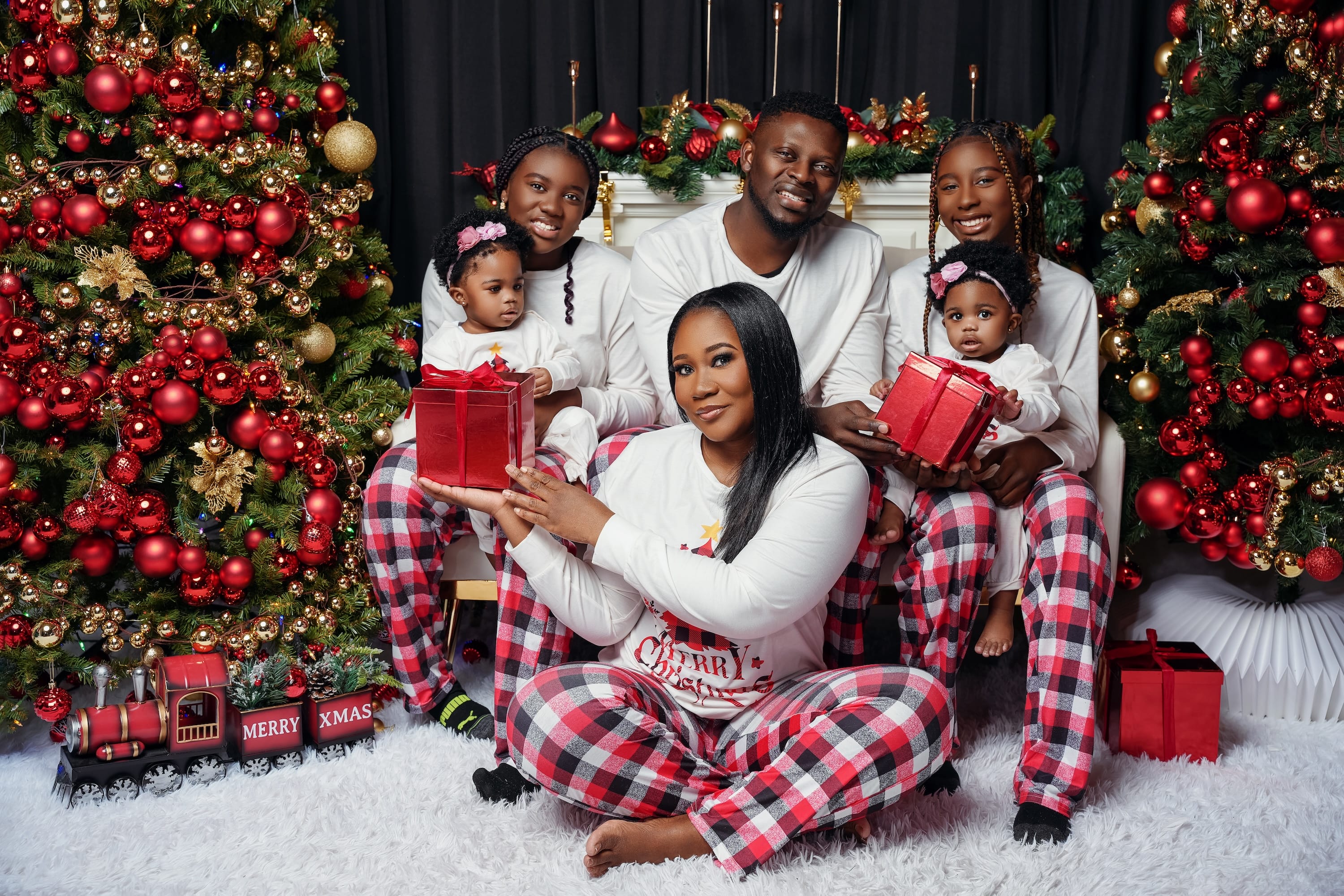 Family in matching pajamas posing beside a decorated Christmas tree