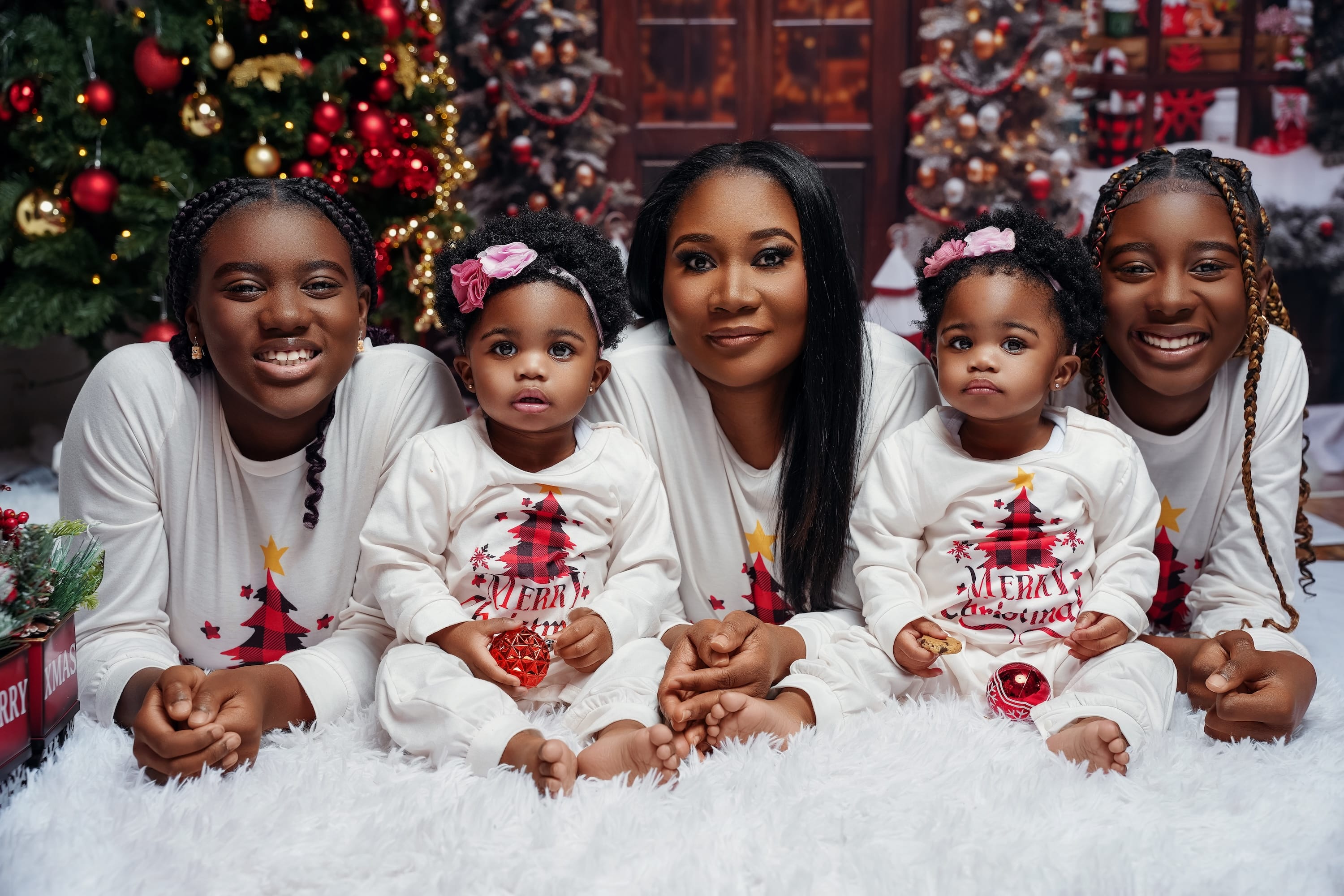 Family in white sweaters gathered beside a decorated Christmas tree