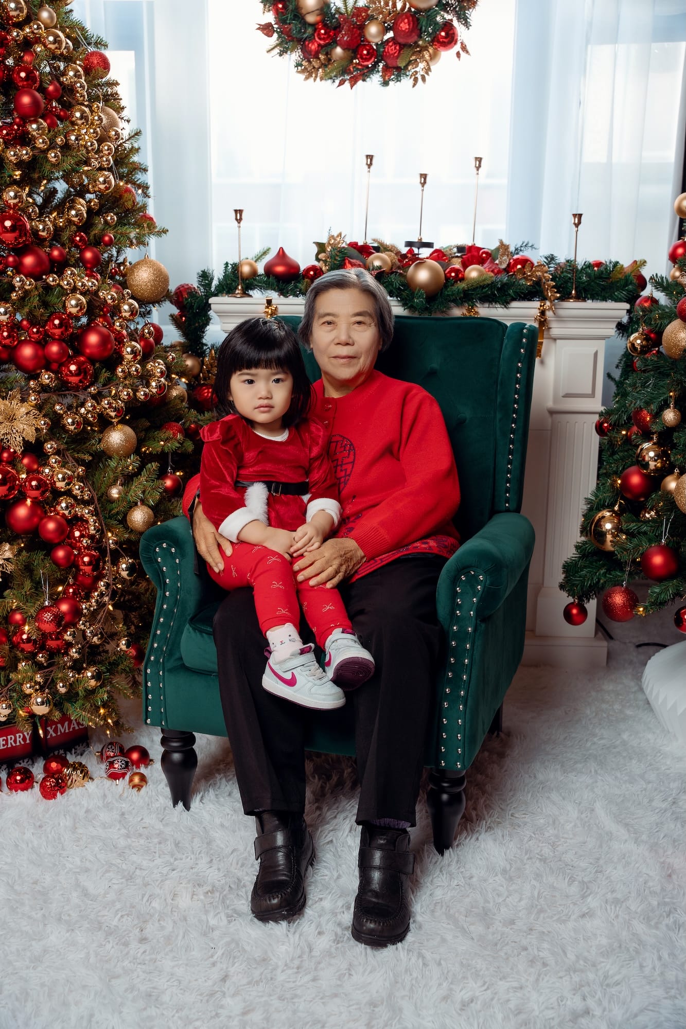 Mother holding her baby in a chair beside a Christmas tree