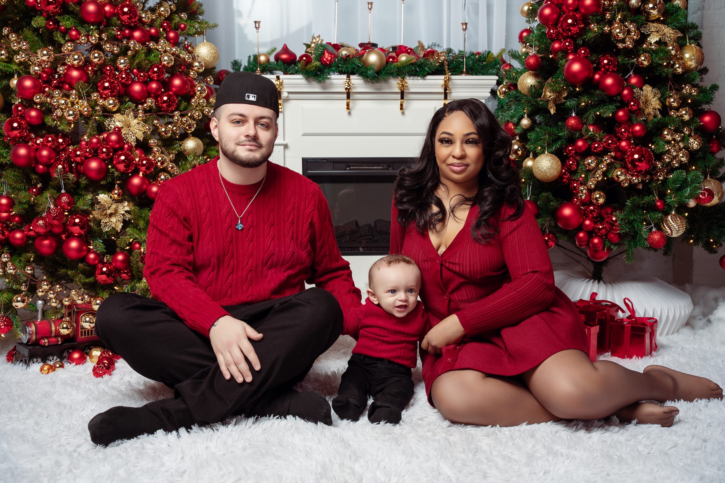 Family in matching red sweaters by the Christmas fireplace
