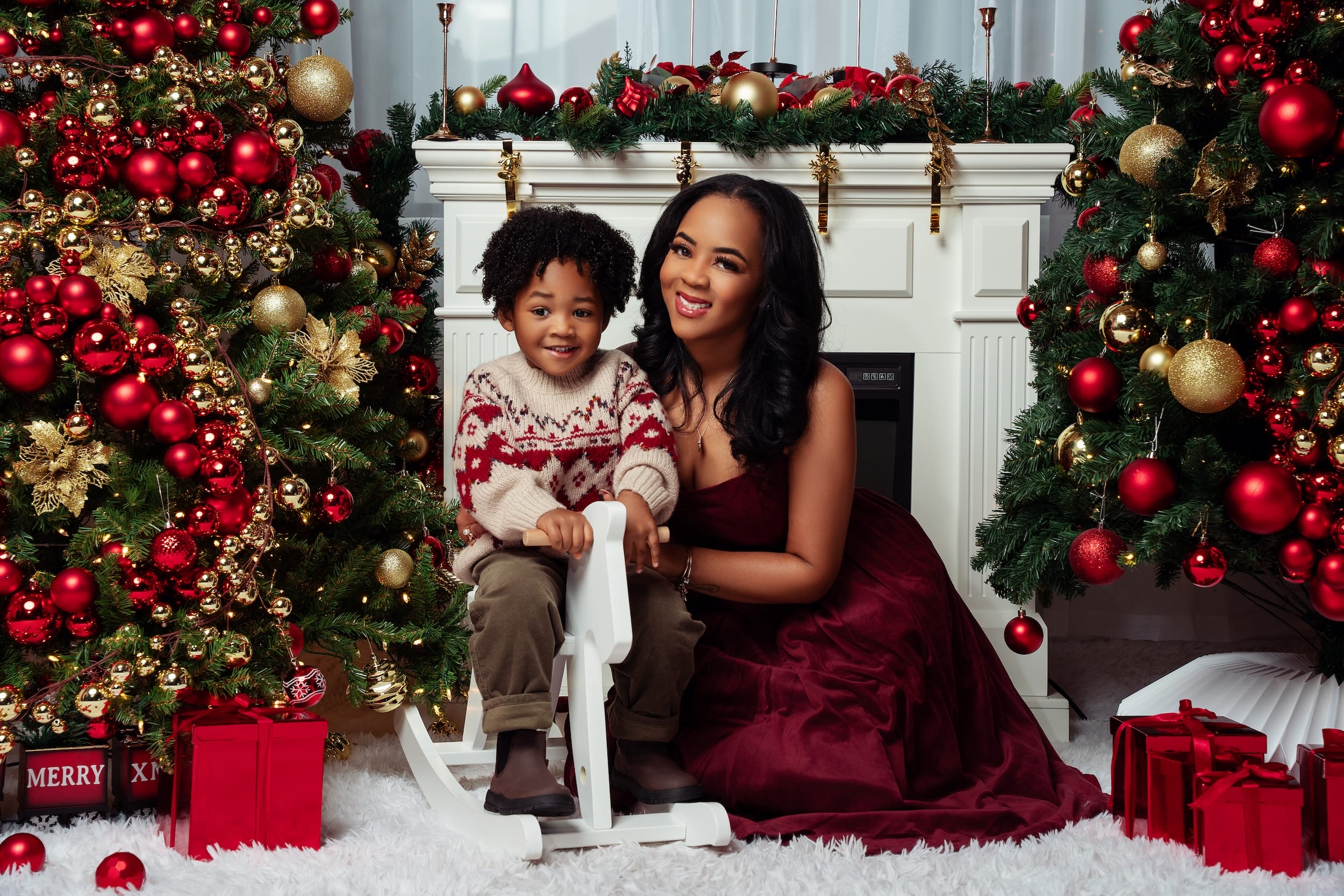 Mother and son Christmas portrait by the fireplace with a rocking horse